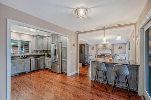 3 Stark Dr, Center Moriches, NY 11934 - kitchen featuring stainless steel appliances, dark countertops, a breakfast bar, backsplash, and dark wood-style flooring