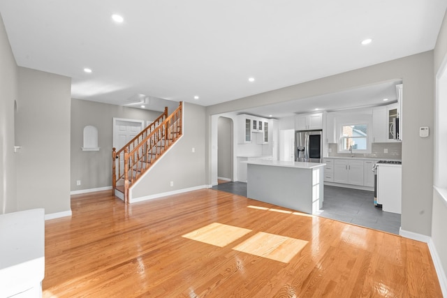 126 Lutz Dr, Valley Stream, NY 11580 - unfurnished living room with light wood-type flooring, recessed lighting, stairs, and arched walkways