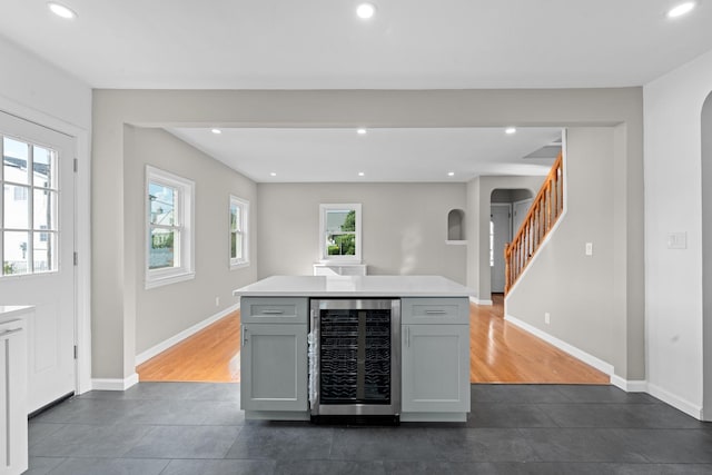 126 Lutz Dr, Valley Stream, NY 11580 - kitchen with beverage cooler, dark tile patterned floors, arched walkways, gray cabinets, and recessed lighting