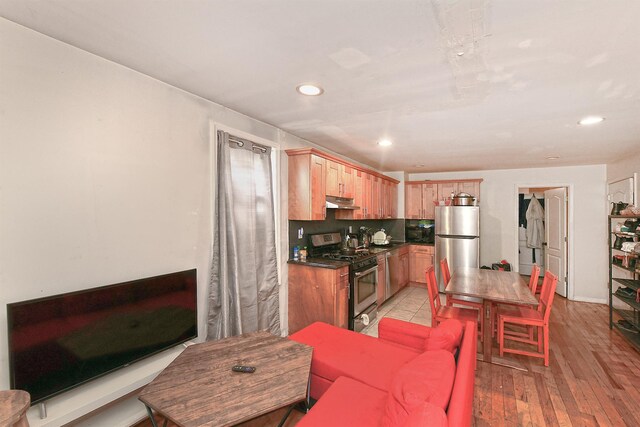 1244 Jefferson Ave, Brooklyn, NY 11221 - kitchen featuring stainless steel appliances, light brown cabinets, dark countertops, under cabinet range hood, and recessed lighting