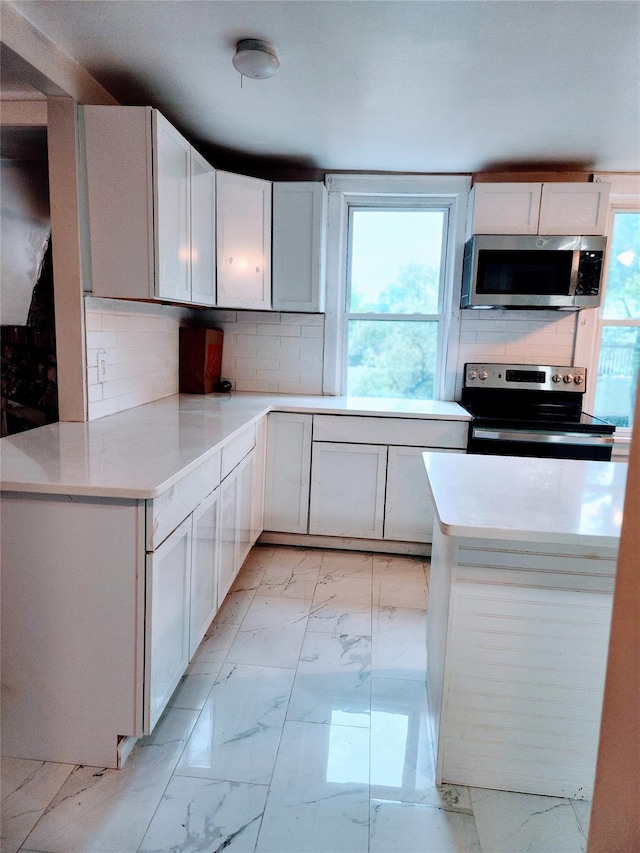 13SLake Drive, Patterson, NY 12563 - kitchen with appliances with stainless steel finishes, light marble finish flooring, backsplash, white cabinets, and light countertops
