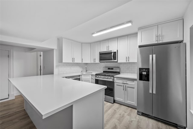 1440 Boston Post Unit 8K, Larchmont, NY 10543 - kitchen featuring stainless steel appliances, a peninsula, light countertops, light wood-style flooring, and decorative backsplash