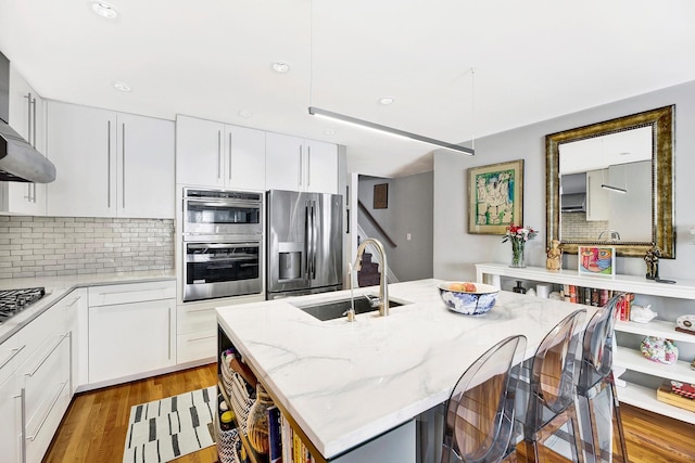 2723 Tilden Ave, Brooklyn, NY 11226 - kitchen featuring appliances with stainless steel finishes, backsplash, a kitchen bar, light wood-style flooring, and recessed lighting