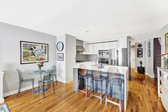 2723 Tilden Ave, Brooklyn, NY 11226 - kitchen featuring stainless steel appliances, wall chimney exhaust hood, light wood finished floors, and tasteful backsplash