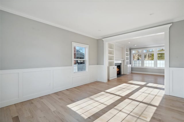 15 Cedar Dr, Old Bethpage, NY 11804 - unfurnished living room featuring plenty of natural light, light wood finished floors, wainscoting, ornamental molding, and a fireplace with flush hearth