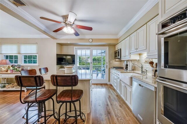 15 Eastover Dr, East Northport, NY 11731 - kitchen with appliances with stainless steel finishes, a breakfast bar area, light wood-type flooring, ceiling fan, and tasteful backsplash