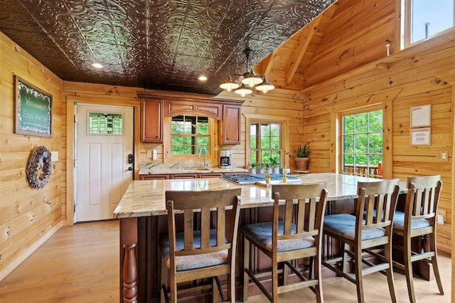 892 Durham Rd, Gilboa, NY 12076 - kitchen featuring wood walls, light wood finished floors, light stone counters, a chandelier, and a kitchen island