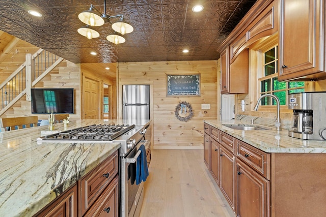 892 Durham Rd, Gilboa, NY 12076 - kitchen with stainless steel appliances, brown cabinetry, a chandelier, light wood finished floors, and wood walls