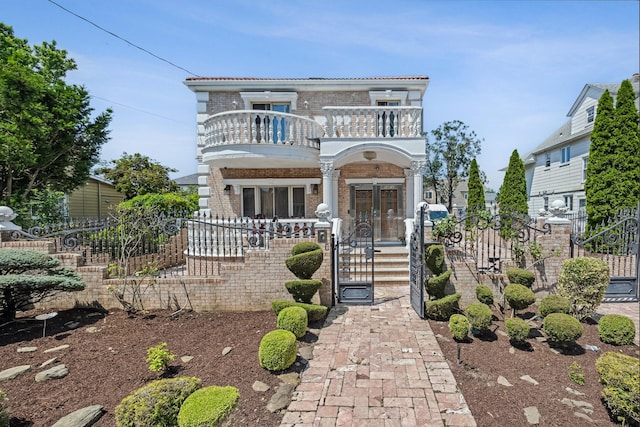 38-16 220th St, Bayside, NY 11361 - view of front of property featuring a balcony, brick siding, a fenced front yard, a gate, and french doors