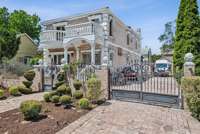 38-16 220th St, Bayside, NY 11361 - view of front facade with a balcony, a gate, a fenced front yard, brick siding, and a chimney