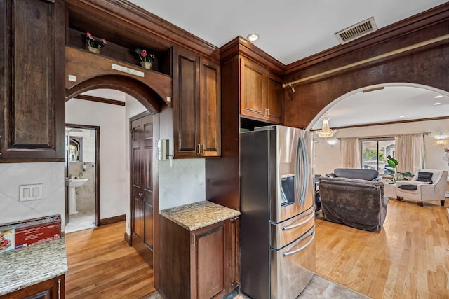 38-16 220th St, Bayside, NY 11361 - kitchen featuring stainless steel fridge with ice dispenser, arched walkways, light wood finished floors, ornamental molding, and light stone countertops