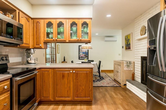 4 Mary Ann Ave, Saugerties, NY 12477 - kitchen with appliances with stainless steel finishes, a wall mounted AC, a peninsula, brown cabinets, and light wood-style flooring