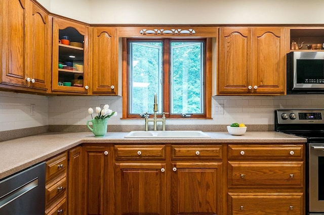 4 Mary Ann Ave, Saugerties, NY 12477 - kitchen featuring stainless steel appliances, brown cabinetry, glass insert cabinets, and backsplash