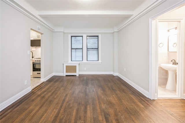 142 E 49th St Unit 4C, New York Manhattan, NY 10017 - spare room featuring radiator, beam ceiling, and dark wood-type flooring
