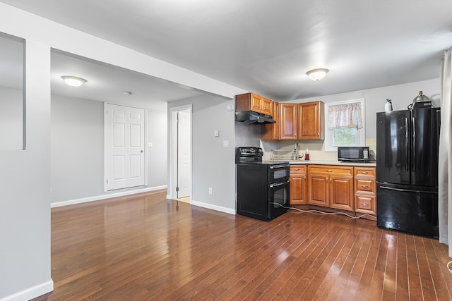 40 Ridge Haven Dr, Ridge, NY 11961 - kitchen with black appliances, under cabinet range hood, dark wood-type flooring, light countertops, and brown cabinetry
