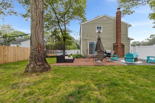 40 Ridge Haven Dr, Ridge, NY 11961 - rear view of house featuring a trampoline, a patio area, a chimney, and a fenced backyard