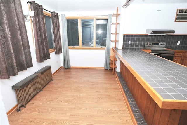 23 Kemble Ave, Cold Spring, NY 10516 - kitchen with electric range, radiator heating unit, tile counters, exhaust hood, and light wood-type flooring