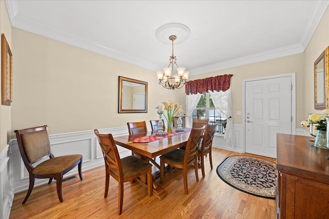 102 Paget Ln, Massapequa, NY 11758 - dining room with a chandelier, crown molding, light wood-style floors, wainscoting, and a decorative wall