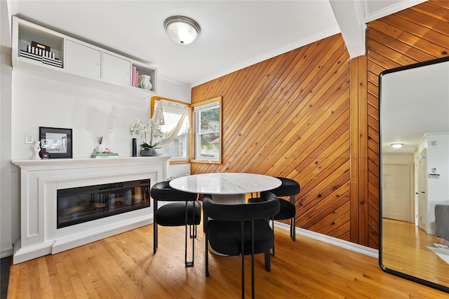 2354 128th St, College Point, NY 11356 - dining space featuring a glass covered fireplace, ornamental molding, light wood-style flooring, and wood walls