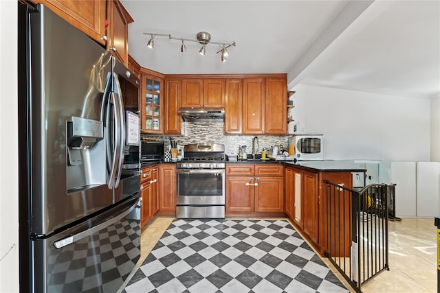 2354 128th St, College Point, NY 11356 - kitchen with appliances with stainless steel finishes, under cabinet range hood, dark countertops, a peninsula, and tasteful backsplash
