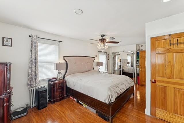 3211 204th St, Bayside, NY 11361 - bedroom featuring wood finished floors, radiator heating unit, and ceiling fan