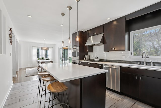 187 Thornbury Rd, Scarsdale, NY 10583 - kitchen with stainless steel appliances, under cabinet range hood, a kitchen breakfast bar, light countertops, and a kitchen island