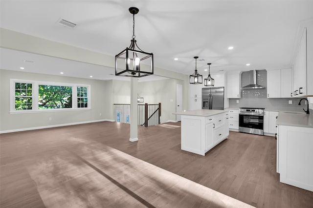 23 White Oak Ln, Bardonia, NY 10954 - kitchen with stainless steel appliances, wall chimney range hood, wood finished floors, a kitchen island, and recessed lighting