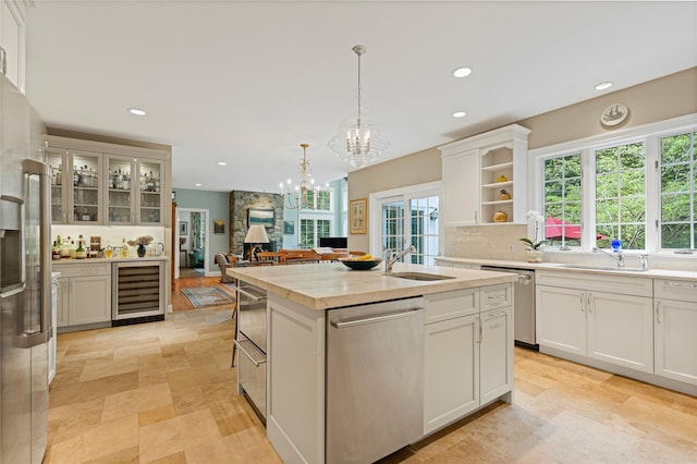 4 Hidden Valley Way, Bedford, NY 10506 - kitchen featuring wine cooler, stainless steel appliances, a center island with sink, light countertops, and white cabinetry