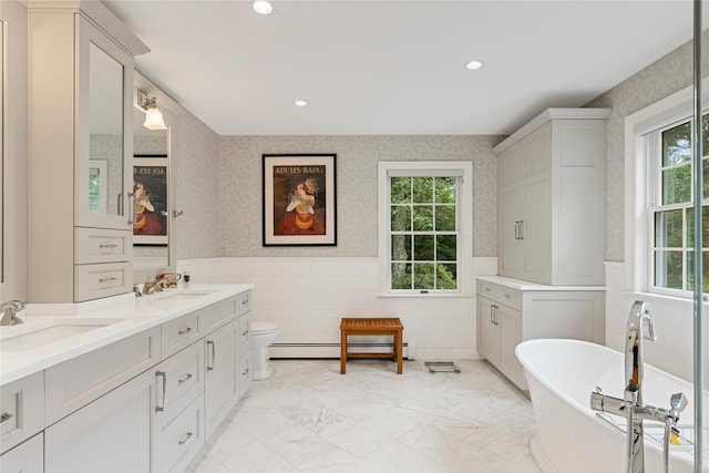 4 Hidden Valley Way, Bedford, NY 10506 - full bath featuring double vanity, a baseboard heating unit, a wainscoted wall, a freestanding bath, and recessed lighting