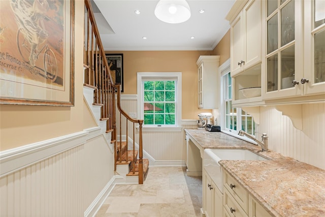 4 Hidden Valley Way, Bedford, NY 10506 - kitchen featuring a wainscoted wall, light stone counters, cream cabinets, glass insert cabinets, and crown molding