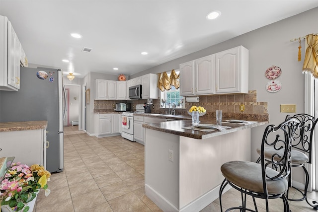40 Rapelje Rd, Walden, NY 12586 - kitchen with stainless steel appliances, a peninsula, white cabinetry, tasteful backsplash, and a kitchen breakfast bar