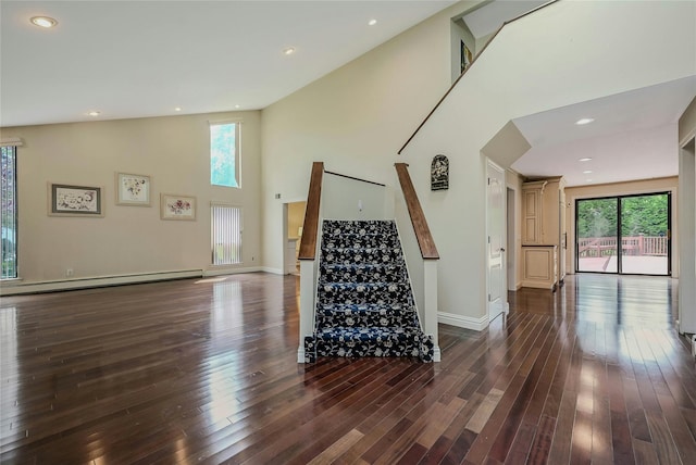 160 Coachman Pl E, Syosset, NY 11791 - unfurnished living room with a baseboard heating unit, plenty of natural light, high vaulted ceiling, stairway, and dark wood-style flooring