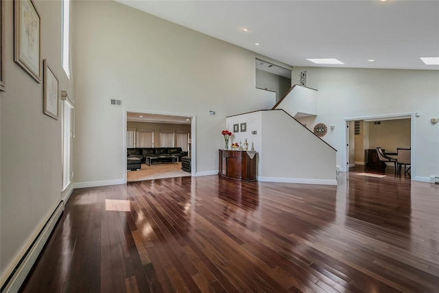 160 Coachman Pl E, Syosset, NY 11791 - unfurnished living room with a baseboard heating unit, high vaulted ceiling, stairs, wood finished floors, and recessed lighting