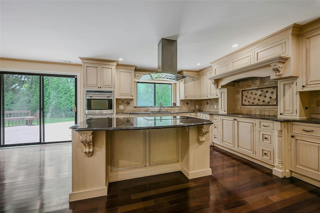 160 Coachman Pl E, Syosset, NY 11791 - kitchen featuring island exhaust hood, cream cabinets, dark wood-style flooring, dark stone countertops, and recessed lighting