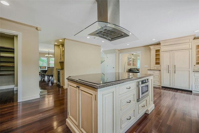 160 Coachman Pl E, Syosset, NY 11791 - kitchen with island exhaust hood, black electric cooktop, dark wood-style floors, a chandelier, and cream cabinets