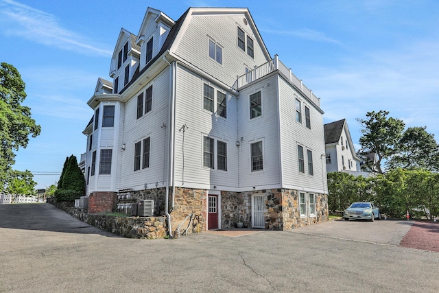 2 Harbor Ln Unit 301, New Rochelle, NY 10805 - view of property exterior featuring stone siding, a balcony, and a gambrel roof