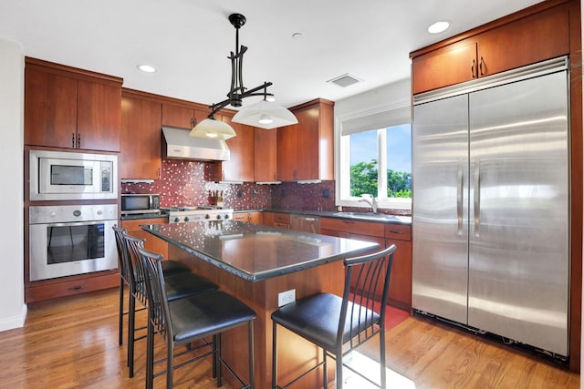 2 Harbor Ln Unit 301, New Rochelle, NY 10805 - kitchen featuring built in appliances, range hood, dark countertops, light wood-style flooring, and recessed lighting