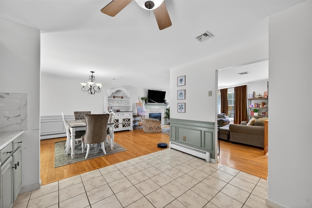 60 Palomino Pl, New Windsor, NY 12553 - dining room with baseboard heating, light tile patterned flooring, ceiling fan, a chandelier, and a fireplace