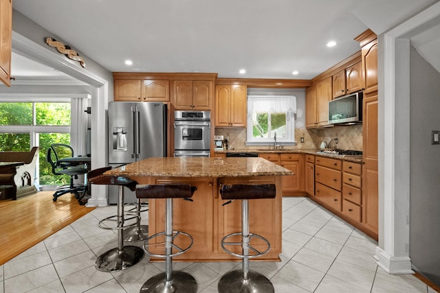 63 Bonnie Meadow Rd, Scarsdale, NY 10583 - kitchen with stainless steel appliances, light stone counters, a center island, light tile patterned floors, and decorative backsplash