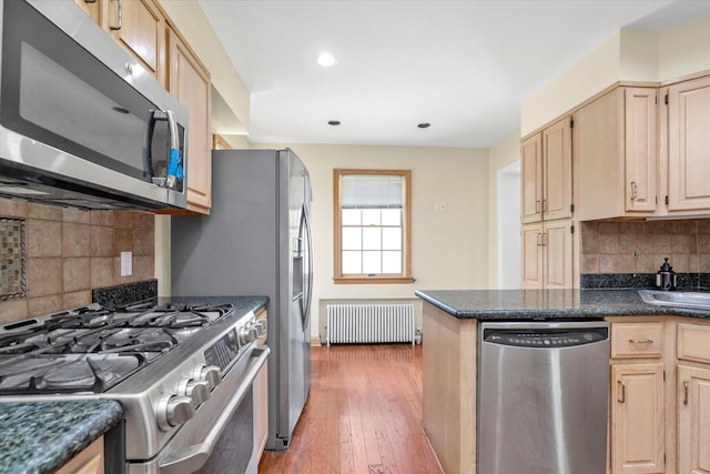 18 Hathaway Dr, Garden City, NY 11530 - kitchen with stainless steel appliances, radiator heating unit, light brown cabinetry, backsplash, and light wood-style floors