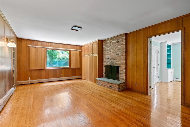 6 Beardsley Ln, Lloyd Harbor, NY 11743 - unfurnished living room featuring baseboard heating, wood walls, light wood-style flooring, a fireplace, and crown molding