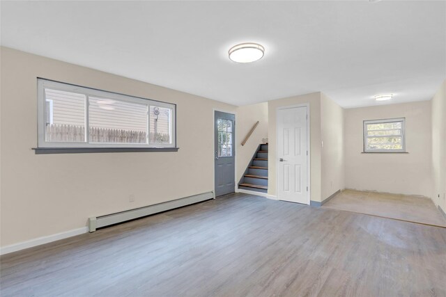 9 Rhodes Ln, West Hempstead, NY 11552 - spare room featuring a baseboard heating unit, stairway, healthy amount of natural light, and wood finished floors