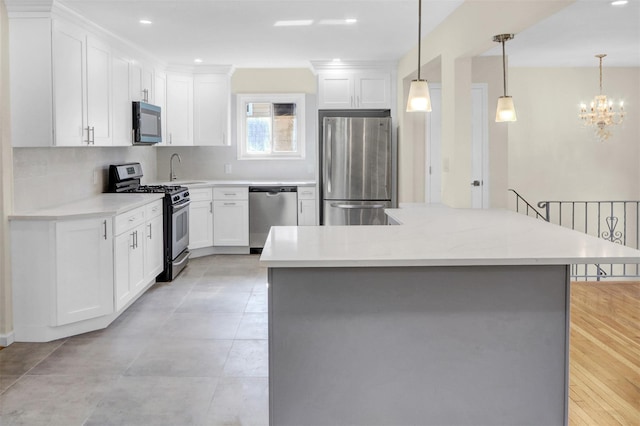 9 Rhodes Ln, West Hempstead, NY 11552 - kitchen featuring stainless steel appliances, white cabinets, light countertops, a chandelier, and pendant lighting