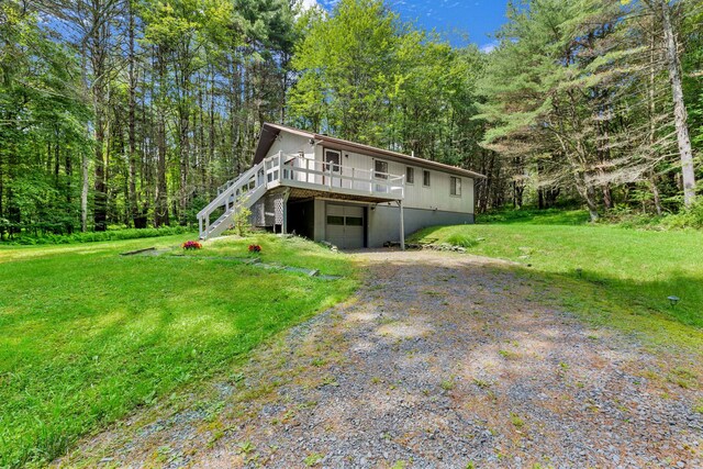 156 Creamery Rd Unit Tr20, Swan Lake, NY 12783 - view of front of property with gravel driveway, a deck, a front lawn, a garage, and a view of trees