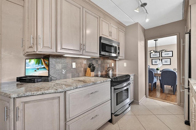 414 Benedict Ave Unit 5B, Tarrytown, NY 10591 - kitchen featuring appliances with stainless steel finishes, decorative backsplash, light tile patterned flooring, and light stone countertops