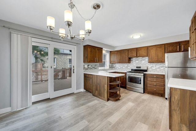 1138 Vincent Ave, Bronx, NY 10465 - kitchen featuring appliances with stainless steel finishes, light wood-type flooring, decorative backsplash, a chandelier, and light countertops