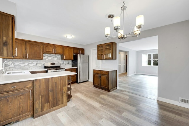 1138 Vincent Ave, Bronx, NY 10465 - kitchen featuring appliances with stainless steel finishes, tasteful backsplash, a chandelier, and light wood-style flooring