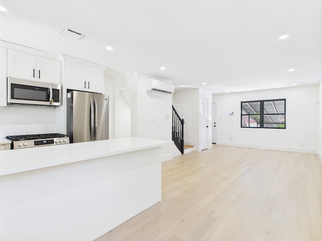 1310 E 223rd St, Bronx, NY 10466 - kitchen featuring appliances with stainless steel finishes, a wall mounted AC, light countertops, white cabinets, and light wood-type flooring