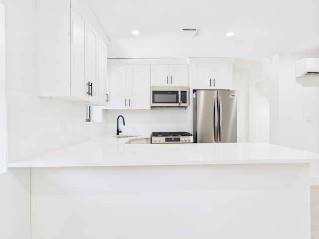 1310 E 223rd St, Bronx, NY 10466 - kitchen with appliances with stainless steel finishes, an AC wall unit, white cabinetry, a peninsula, and recessed lighting