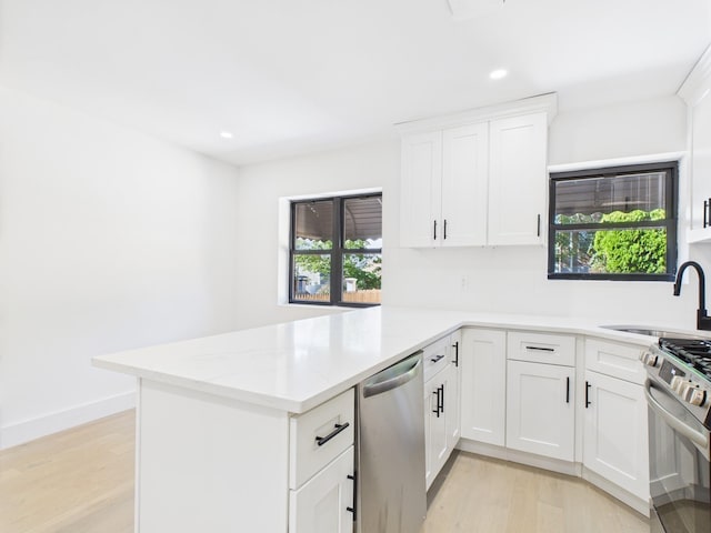 1310 E 223rd St, Bronx, NY 10466 - kitchen featuring stainless steel appliances, a peninsula, light wood-style floors, white cabinetry, and recessed lighting